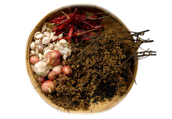 isolated dried chilies, Zanthoxylum, garlic cloves and shallots on a bamboo basket on a white...