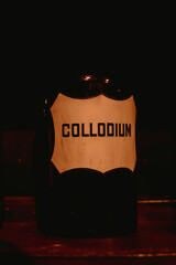 A bottle of Collodium on a shelf in darkness - 725728230