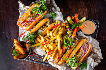 fast food set on plate. hot dog,  burger, potato chips, french fries, vegetables, hashbrown and more on table