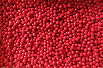 Closeup red dragee, chocolate covered nuts, sweet candy background