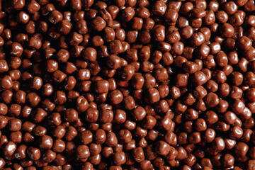Closeup brown dragee, chocolate covered nuts, sweet candy background