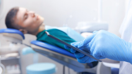 Closeup Dentist use digital tablet, background client patient man, banner technology in modern...