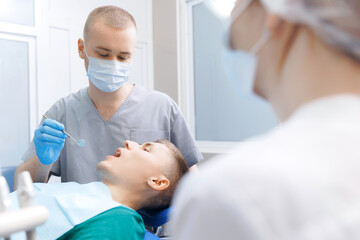 Dentistry clinic banner, young men getting dental checkup. Dentist using equipment probe and mirror...