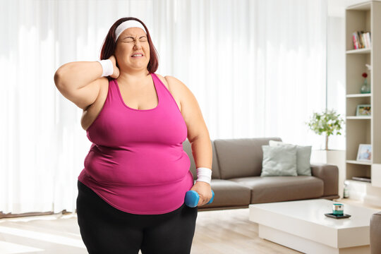 Plus size woman with a dumbbell holding her stiff neck