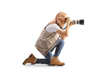 Full length profile shot of a female photographer kneeling and taking a photo - obrazy, fototapety, plakaty