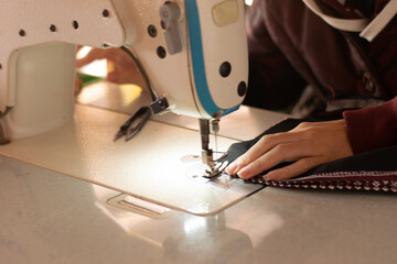 Female hands sewing with modern sewing machine at work The process of sewing, upholstery, clothing, repair.