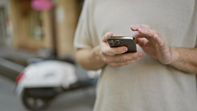 A focused young adult man holding a smartphone on a busy city street, showcasing urban connectivity and lifestyle.
