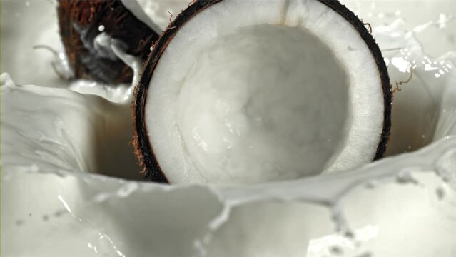 Half of the coconut falls into the milk with splashes. Filmed on a high-speed camera at 1000 fps. High quality FullHD footage