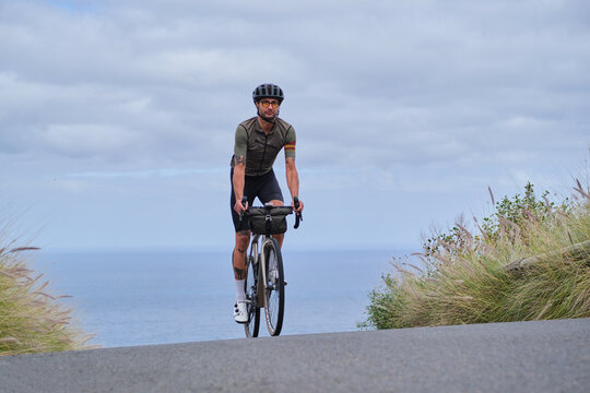 A male cyclist is riding a bicycle on the road. Training for competition. Practicing cycling on open country road. Cycling adventure on Tenerife, Canary Island.