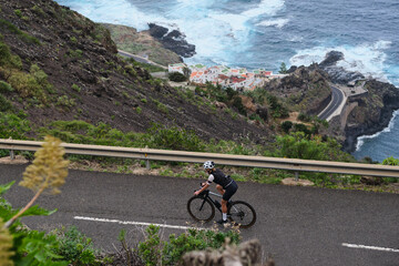 Top view of woman cyclist riding a road bike with a view of the mountains and ocean. Cycling...