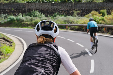 Close-up rear view of a woman and a man cycling on an empty mountain road on Tenerife. Cycling adventure. Sportsmen cycling in the beautiful natural surroundings. Masca canyon, Canary Island, Spain.