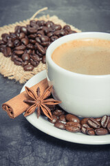 Coffee in white cup and roasted dark coffee beans with seasonings