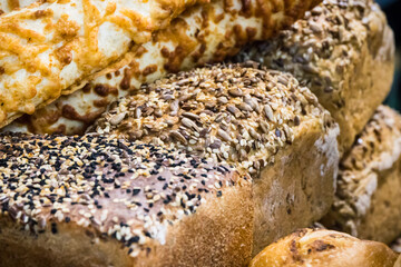 Fresh traditional loaves of wheat or rye bread with grains on stall or in bakery