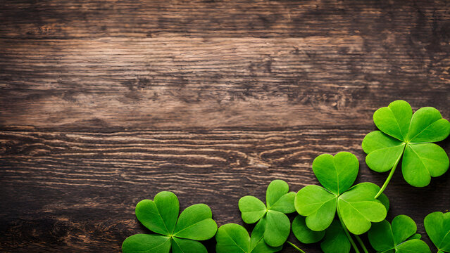 st patrick day background, green shamrocks on dark wood with copyspace - Powered by Adobe