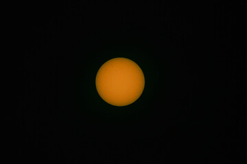 Tarcza słoneczna sfotografowana z użyciem teleobiektywu. W wyniku zastosowania filtra optycznego uzyskano ciepłą barwę tarczy słonecznej. Widoczne są plamy na powierzchni słońca. - obrazy, fototapety, plakaty