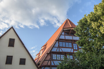 Historisches Fachwerkhaus mit Walmdach, Dachgauben und Sprossenfenstern vor blauem Himmel mit Wolken im Gerberviertel in Nördlingen