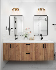 A bathroom with a floating wood vanity cabinet, decorations on the white marble countertop, gold...