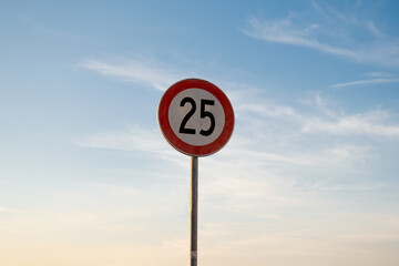25 miles km maximum speed limit traffic sign isolated with sunset sky