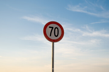 70 miles km maximum speed limit traffic sign isolated with sunset sky