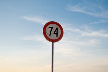 74 miles km maximum speed limit traffic sign isolated with sunset sky