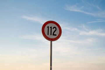 112 miles km maximum speed limit traffic sign isolated with sunset sky
