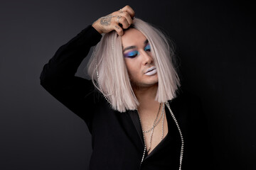 self-confident transvestite or gay take off the wig from head, male with make-up on face, isolated...