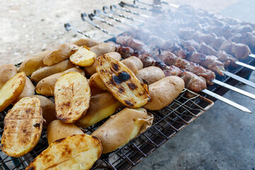 Grilled potatoes and meat skewers on barbecue grill