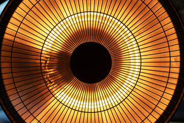 Detailed close up view of round electric heater in orange and yellow color as abstract tech...
