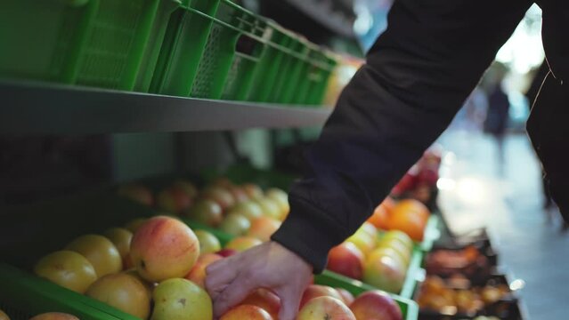 Customer choose natural organic apple fruit neatly displayed on street store shelves.