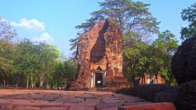 The ruins of an old castle built with laterite bricks of the ancient city of Si Thep..Ancient Angkor Temple Tower Amidst Park's Historic Stone Ruins and Towering Trees .in Si Thep Historical Park.