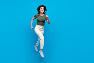 Fototapeta na wymiar Full length photo of good mood positive girl dressed khaki t-shirt flying run shopping in empty space isolated on blue color background