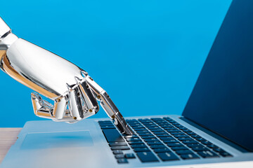 Robot hand typing on laptop