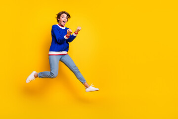 Fototapeta na wymiar Full length photo of lucky cool lady dressed knitted sweater jumping high rising fists empty space isolated yellow color background