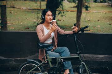 Obraz premium Happy young Asian woman while riding a bicycle in a city park. She smiled using the bicycle of transportation. Environmentally friendly concept.
