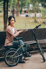 Obraz premium Happy young Asian woman while riding a bicycle in a city park. She smiled using the bicycle of transportation. Environmentally friendly concept.