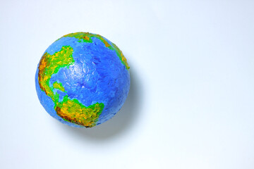 Planet earth on a light blue background. Toy model of the globe. World ecology and environmental problems. Top view, place for text.