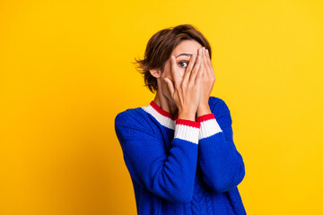 Photo portrait of attractive young woman hide face watch horror movie wear trendy blue knitwear clothes isolated on yellow color background