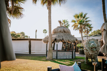 Sotogrante, Spain - January 25, 2024 - A sunny beach setting with palm trees, thatched huts, a lion...