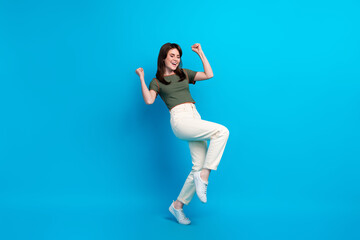 Fototapeta na wymiar Full size photo of glad delighted girl raise fists shout yes success achieve isolated on blue color background