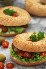 Sesame bagels with tomatoes, ham and olives	