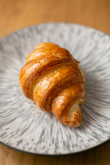 Croissant on a grey plate on a wooden background