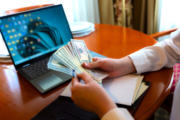 Young beautiful european woman using laptop counting dollars at home