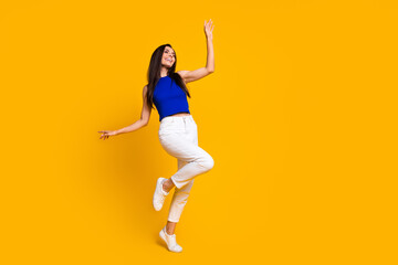 Fototapeta na wymiar Full length photo of cute carefree woman wear blue top dancing having fun empty space isolated yellow color background