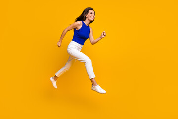 Fototapeta na wymiar Full length photo of excited shiny woman wear blue top jumping running fast empty space isolated yellow color background