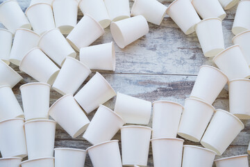 White paper cups scattered on the table and an empty space among them. Background of empty paper...