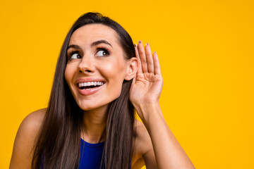 Photo of funny cheerful lady dressed blue top arm ear looking listening empty space isolated yellow...