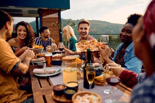 Cheerful friends enjoying in meal at dinning table on patio.