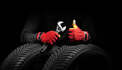 Winter car tires service and hands of mechanic with wrench, screwdriver on black background. - 725811008