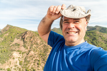 Happy man with a hat takes a selfie photo outdoors. 