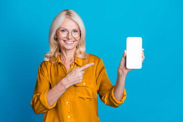 Photo of attractive pensioner woman hold device point white screen dressed stylish yellow satin...